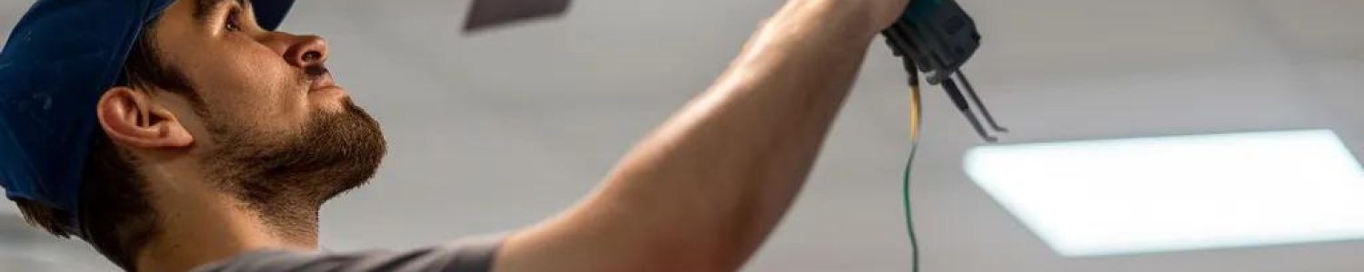 Electrician installing a ceiling fan in a modern office, highlighting same-day installation services